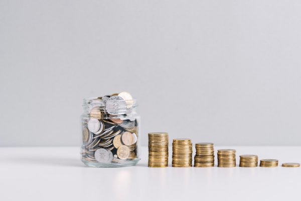 glass-jar-full-money-front-decreasing-stacked-coins-against-white-background